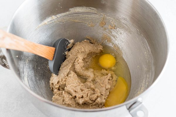  Добавление яиц к маслу и сахару для домашнего печенья с шоколадной крошкой. 